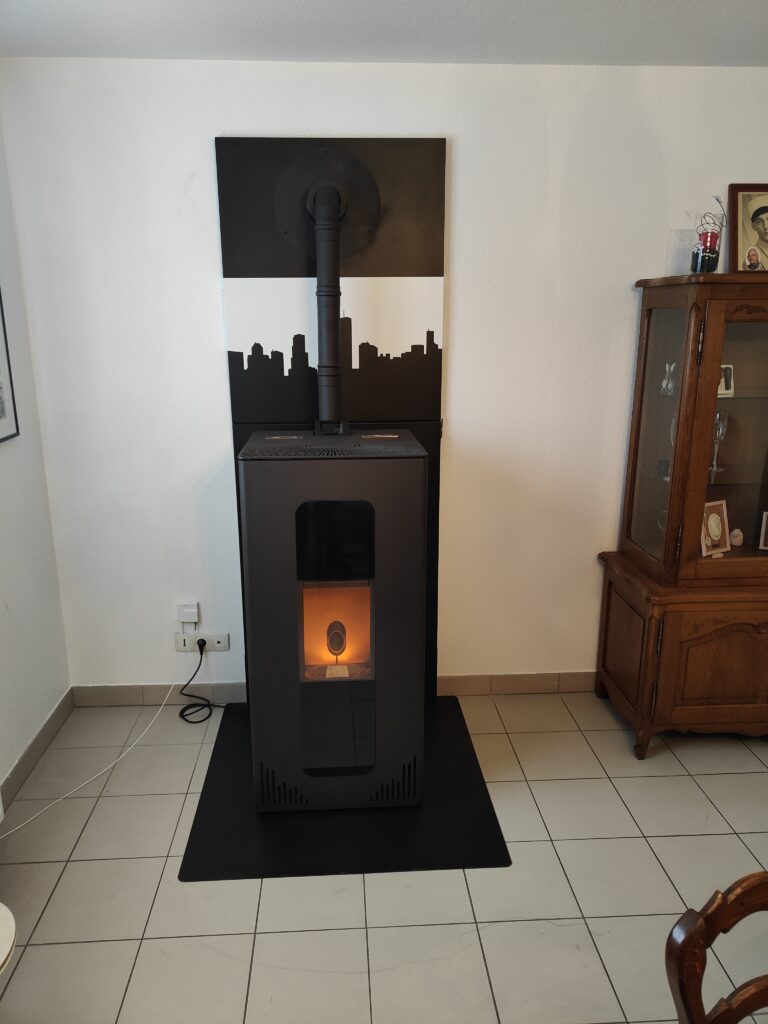 Installation d'un poêle à granulés noir rectangulaire avec une fine fumisterie noir dans une salle à manger