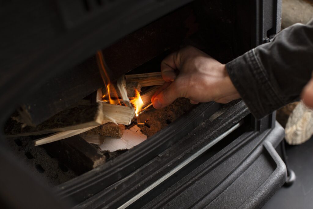 Installateur allumant un feu pour vérifier l'étanchéité de l'installation de chauffage bois