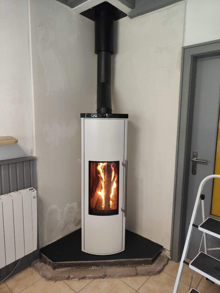 Poêle à bois blanc cylindrique posé sur un socle réhausse noir
