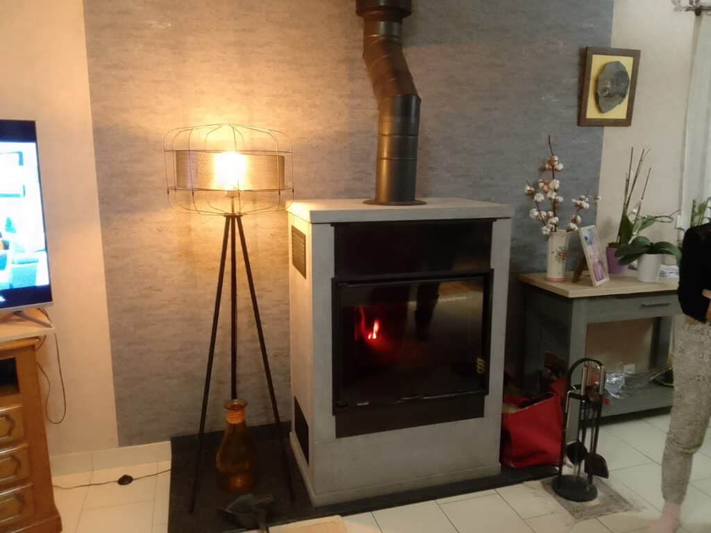Un insert bois dans un habillage de cheminée ollaire avec grosse fumisterie noire