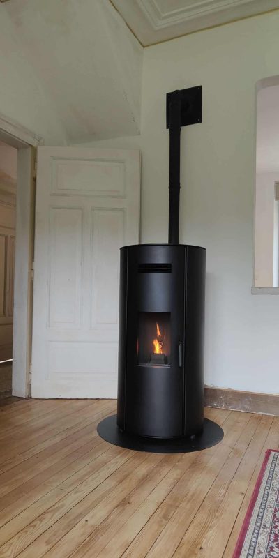 Gros poêle noir à granulée dans une pièce en rénovation